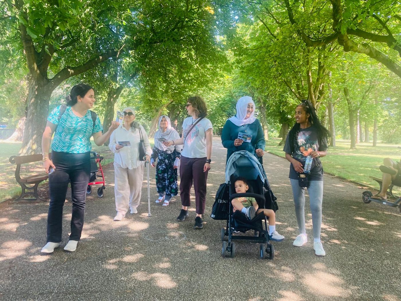 A group of women walking and talking together along a tree-lined path in Albert Park.