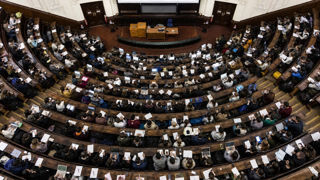 A university lecture theatre seen from above, filled with students.